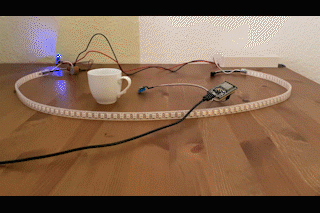 Gif-Animation, die einen LED-Streifen zeigt der zunächst grün blinkt. In eine Espressotasse wird Wasser eingegossen. Weitere Elektronik im Bild (Sensor) wird über die Tasse gehalten. Das Blinken wird schneller und die Farbe wechselt langsam zu rot.
