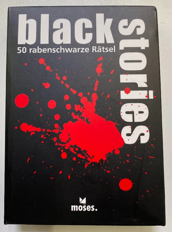 Spielverpackung, roter Blutfleck auf schwarzem Grund. Text: Black Stories 50 rabenschwarze Rätsel. Unten mittig: Logo moses-Verlag